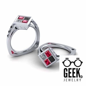 May include: A silver ring with a square-shaped red, black, and white gemstone setting. The ring is designed with a diamond pattern on the band.