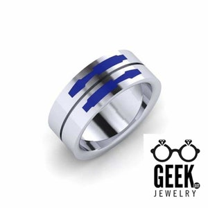 May include: A silver-colored ring with a blue geometric design. The ring has a flat band with a groove and blue inlays. The Geek Jewelry logo is in the lower right corner.