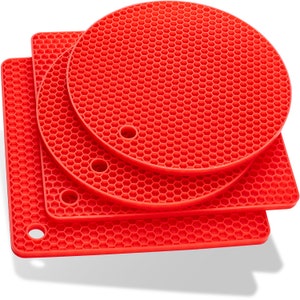 May include: Set of three red silicone hot pads with a honeycomb pattern. The pads are in different sizes and shapes, including a round pad and two square pads.