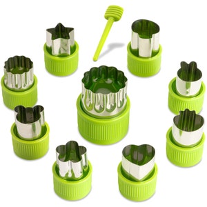 Puede incluir: Un juego de cortadores de verduras de acero inoxidable en varias formas, incluyendo una estrella, un corazón y una flor, con bases de plástico verde. También se incluye una pequeña herramienta verde con mango acanalado. Estos cortadores están diseñados para la preparación de alimentos.