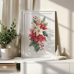 以下が含まれることがあります： 赤と白の花、緑の葉、赤い実のポインセチアのアレンジメントが描かれた、額入りの水彩画プリント。このアートワークは、植物、本、装飾品が置かれた白いキャビネットに飾られています。