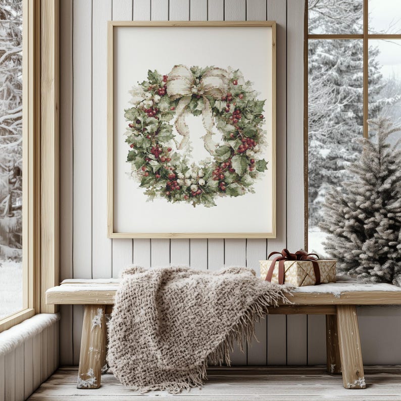 May include: A framed print of a Christmas wreath with red berries, green leaves, and a large beige bow. The print hangs above a wooden bench with a beige blanket and a wrapped gift. A snowy winter scene is visible through a window.