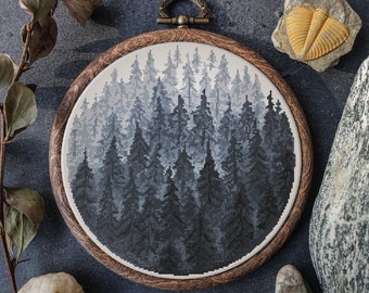 May include: A round wooden embroidery hoop with a black and white cross-stitch design of a forest. The forest is made up of many trees, all of which are dark blue and gray.