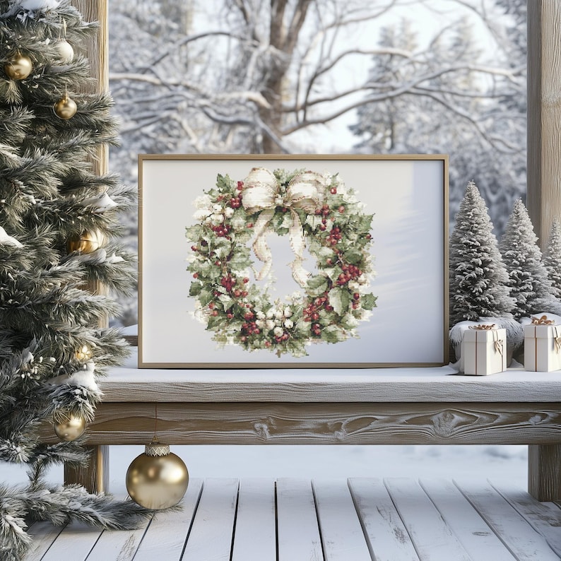 May include: A framed print of a Christmas wreath with red berries, green leaves, and a cream-colored bow. The print is displayed on a wooden bench with miniature Christmas trees and wrapped gifts. A Christmas tree with gold ornaments is on the left.