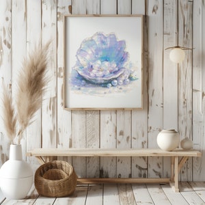 Könnte beinhalten: Ein gerahmtes Aquarellbild eines großen Muschels mit einer Perle darin. Die Muschel ist helllila und blau mit einer weißen Perle darin. Der Hintergrund ist ein hellblauer Aquarell-Wasch.