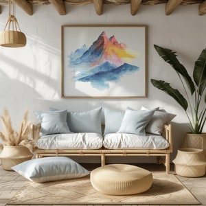 May include: A light blue sofa with white cushions and a light brown wooden frame. The sofa is in front of a white wall with a framed watercolor painting of a mountain range in shades of blue, pink, and yellow. A light brown woven ottoman sits in front of the sofa.