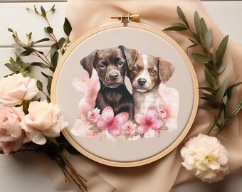 May include: Embroidered hoop art featuring two adorable puppies with brown and white fur, surrounded by pink watercolor flowers. The puppies are looking at the viewer with sweet expressions.