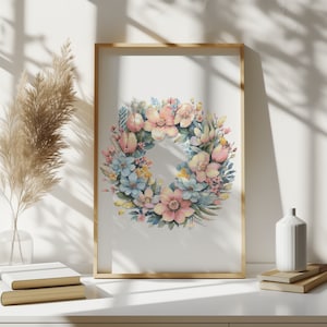Puede incluir: Una pintura de acuarela enmarcada de una corona de flores con flores rosas, azules y amarillas. La corona está sobre un fondo blanco.