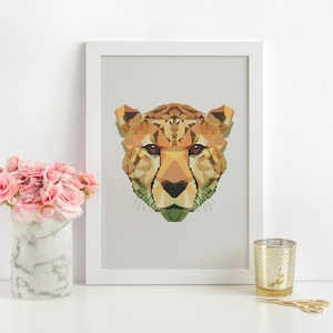 May include: A framed print of a geometric cheetah head in shades of orange, brown, and green. The print is displayed on a white wall with a vase of pink flowers and a gold candle holder on a white surface.