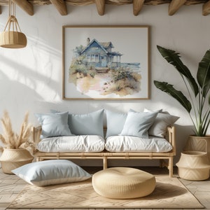 May include: A light blue couch with two pillows sits in a living room with a watercolor painting of a blue house on the wall. A woven basket sits on the floor next to a large potted plant with green leaves. A woven footstool sits in front of the couch.