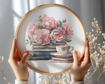 May include: A framed cross-stitch embroidery featuring a bouquet of pink peonies, a stack of books, and a teacup and saucer. The embroidery is set against a white background.