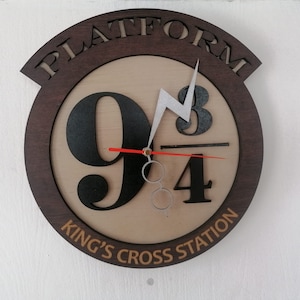 May include: A brown wooden clock with a white lightning bolt and the numbers 9 3/4. The clock face also says "Platform" and "King's Cross Station".