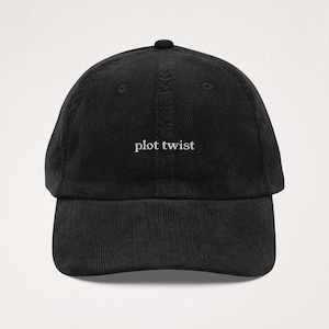 Puede incluir: Gorra de béisbol negra de pana con visera curva. La gorra presenta la frase "plot twist" bordada en blanco en el centro. Tiene una corona estructurada y una correa ajustable en la parte trasera.