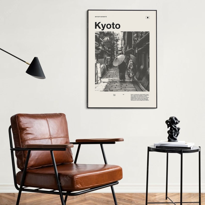May include: Black and white photograph of a street in Kyoto, Japan. Two people walk down the street, one holding an umbrella. The image is framed in a black frame and has the text "Kyoto" in bold white letters at the top.