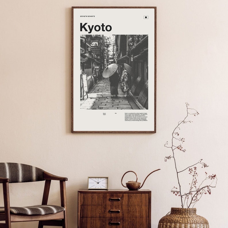 May include: A black and white photograph of a narrow street in Kyoto, Japan. Two people are walking under umbrellas. The image is framed with a white border and the word "Kyoto" is printed in bold black letters at the top.
