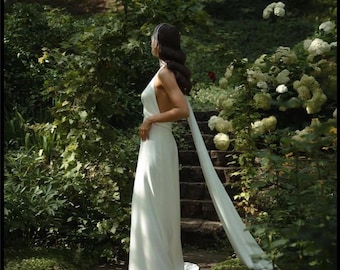 Vestido de novia sencillo de seda, con escote halter, espalda descubierta y cola, corte al bies.