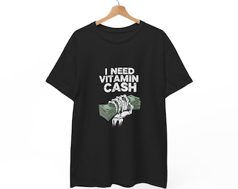 May include: Black t-shirt with the text "I NEED VITAMIN CASH" in white. A skeletal hand is holding a stack of green money. The shirt is hanging on a wooden hanger.