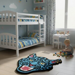 May include: A child's bedroom with a white bunk bed, blue and yellow striped bedding, and a blue rug shaped like a jaguar's head. The room has a light blue wall with star and cloud decals.
