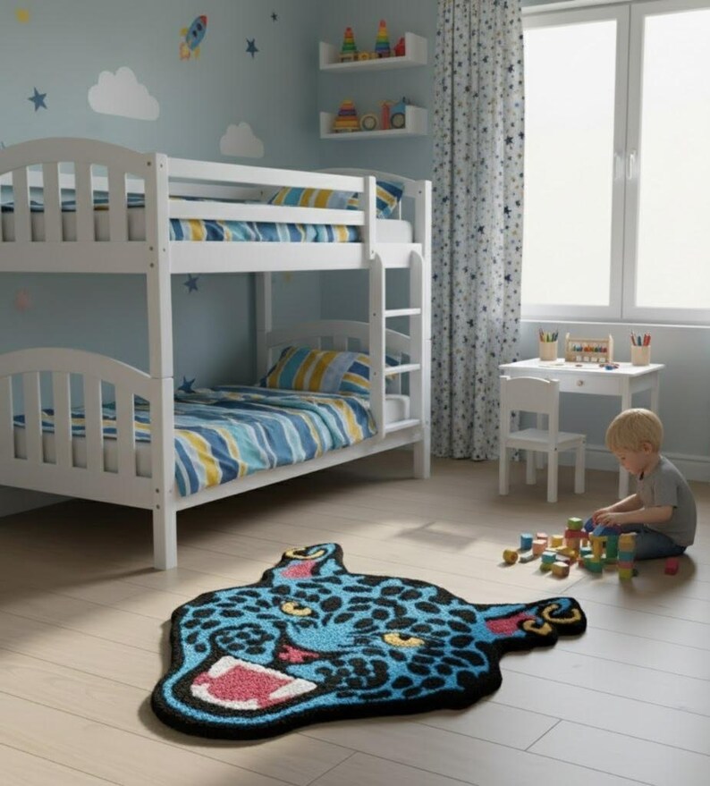 May include: A child's bedroom with a white bunk bed, blue and yellow striped bedding, and a blue rug shaped like a jaguar's head. The room has a light blue wall with star and cloud decals.