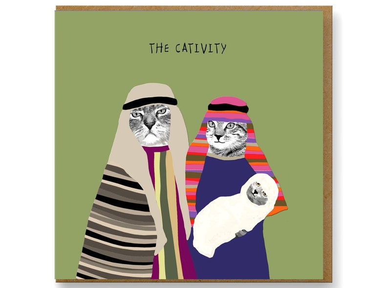 May include: Greeting card with the text "THE CATIVITY" on a green background. The card features a humorous illustration of two cats dressed in religious attire, with one holding a white lamb. The card is in a brown frame.