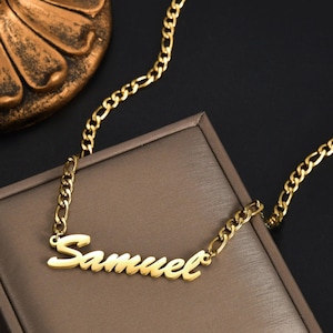 Pu&ograve; includere: Una collana color oro con un ciondolo a forma di targhetta con il nome Samuel scritto in corsivo. Il ciondolo &egrave; fissato a una catena color oro in stile figaro, composta da un motivo di tre maglie circolari piccole e una maglia ovale allungata.
