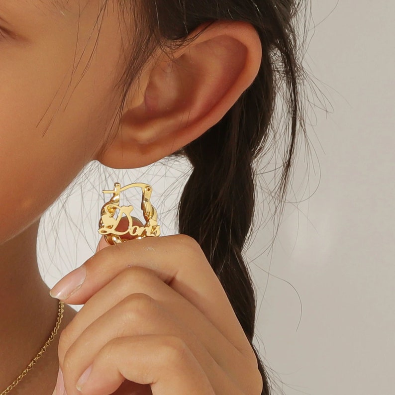 May include: Gold hoop earrings with the word "Doris" spelled out in cursive.