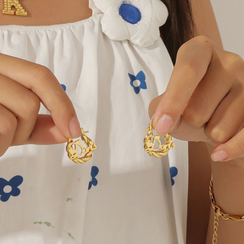May include: Gold hoop earrings with the word "Doris" spelled out in a twisted rope design.