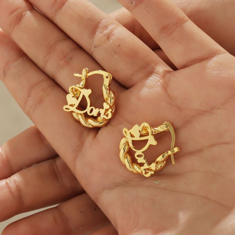 May include: Gold hoop earrings with the name "Doris" written in cursive on each earring.