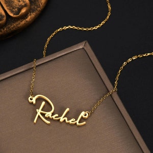 Pu&ograve; includere: Una collana color oro con un ciondolo a forma di targhetta con il nome Rachel scritto in corsivo. Il ciondolo &egrave; fissato a una delicata catenina color oro con piccoli anelli ovali, creando un gioiello continuo con una finitura lucida.