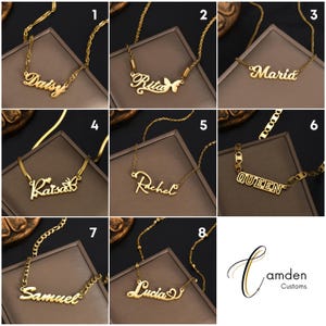 Pu&ograve; includere: Una collezione di otto collane con nome in metallo dorato in vari caratteri, alcune decorate con motivi a farfalla o a cuore. Ogni collana &egrave; esposta su una base quadrata marrone scuro e mostra i nomi Daisy, Rita, Maria, Raisa, Rachel, Queen, Samuel e Lucia.