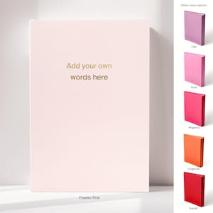 May include: A powder pink notebook with the text "Add your own words here" in gold lettering. Additional colour options include lilac, rose, magenta, tangerine, and scarlet. The notebook is displayed on a white surface.