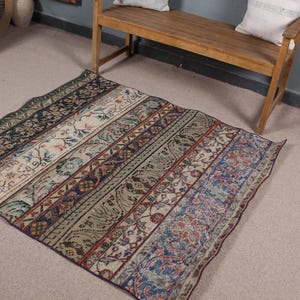 May include: A rectangular area rug featuring a series of vertical panels with intricate floral and geometric patterns in shades of blue, red, green, and cream. The rug has a dark border and a distressed, weathered appearance across the surface.