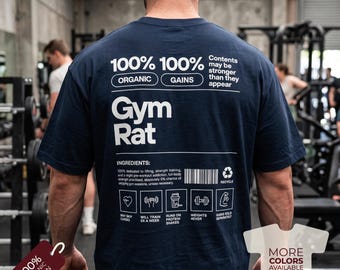 May include: A navy blue short-sleeve t-shirt with white text on the back. The design features the words 100% Organic, 100% Gains, Gym Rat, and a list of ingredients with icons including a heart, dumbbells, a shaker bottle, and a barcode.