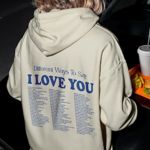 Sudadera con capucha "Diferentes maneras de decir 'Te amo'" – Estampado tipográfico romántico en la espalda, regalo unisex acogedor