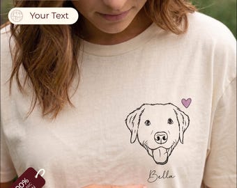 Puede incluir: Una camiseta de color crema con una ilustración de línea negra de la cara de un perro en el pecho. Sobre el perro hay un pequeño corazón morado y debajo de la ilustración está el nombre Bella escrito en una fuente cursiva.