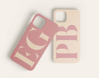 May include: Two phone cases with a pink and cream color scheme. The cases feature the letters "B" and "G" in a bold, stylized font.