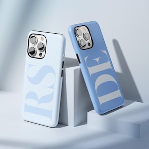 May include: Two blue phone cases with white lettering. The case on the left says "RS" and the case on the right says "DE".