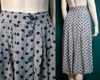 May include: A gray skirt with a navy blue polka dot pattern. The skirt has a button closure and a high waist.