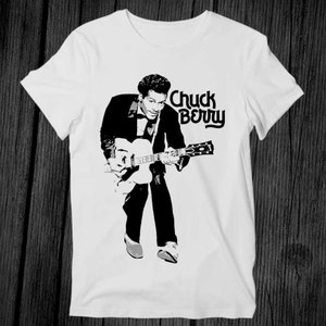 May include: White t-shirt with a black and white image of Chuck Berry playing a guitar. The text "Chuck Berry" is printed in black above the image.