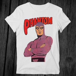 May include: White t-shirt with a purple and red graphic of The Phantom, a masked superhero, with the text "PHANTOM" in red.