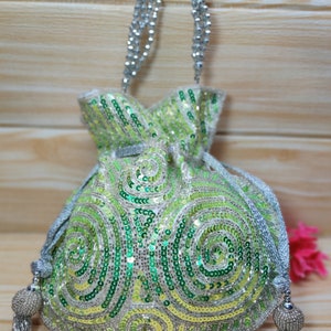 May include: A green and silver sequined drawstring bag with a silver chain strap and tassel. The bag has a swirling pattern.