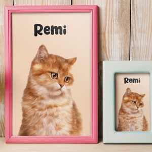 K&ouml;nnte beinhalten: Zwei gerahmte Bilder einer Katze namens Remi. Der gr&ouml;&szlig;ere Rahmen ist rosa und der kleinere Rahmen ist hellblau.
