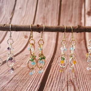 May include: Six pairs of dangle earrings with multiple gold and silver rings and crystal beads in various colors, including purple, green, blue, and orange.