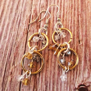 May include: Gold and silver tone earrings with multiple dangling circles and crystal beads.