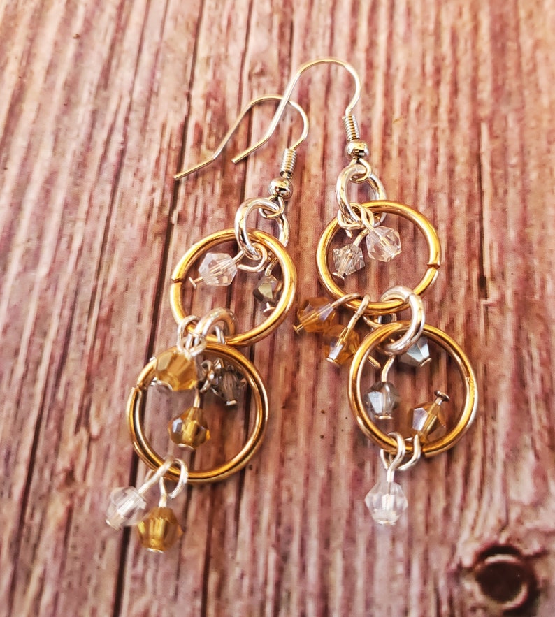 May include: Gold and silver tone earrings with multiple dangling circles and crystal beads.