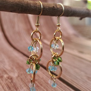 May include: Gold dangle earrings with multiple linked circles and blue, green, and clear crystal beads.