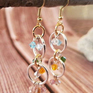 May include: Gold and silver hoop earrings with dangling crystal beads in shades of blue, green, orange, and pink.