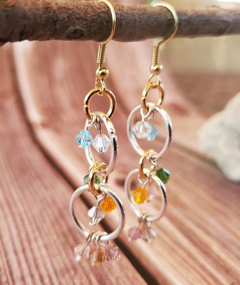 May include: Gold and silver hoop earrings with dangling crystal beads in shades of blue, green, orange, and pink.
