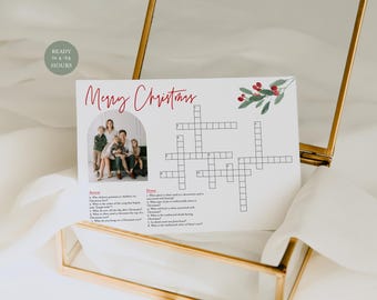 May include: A white Christmas-themed crossword puzzle card with the words "Merry Christmas" in red script. The card features a family photo and a watercolor illustration of holly berries. The card is displayed in a gold-framed glass box.