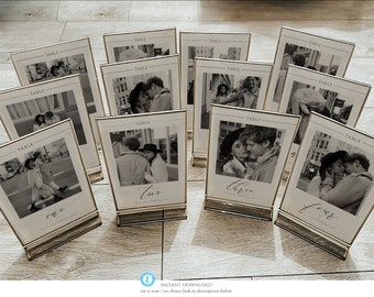 May include: Ten gold-framed table number cards with black and white photos of couples. The numbers are written in calligraphy and include "one", "two", "three", and "four".
